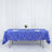 Blue geometric tablecloth on a dining table with white flowers and glassware.