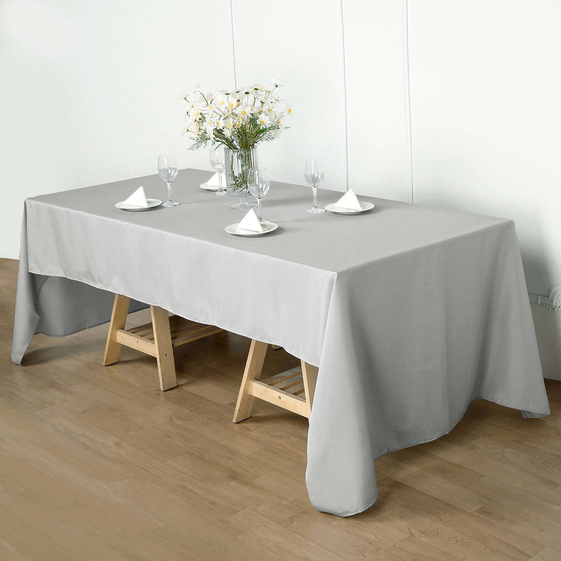 Gray tablecloth draped over a wooden table set for dining.