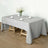 Gray tablecloth draped over a wooden table set for dining.