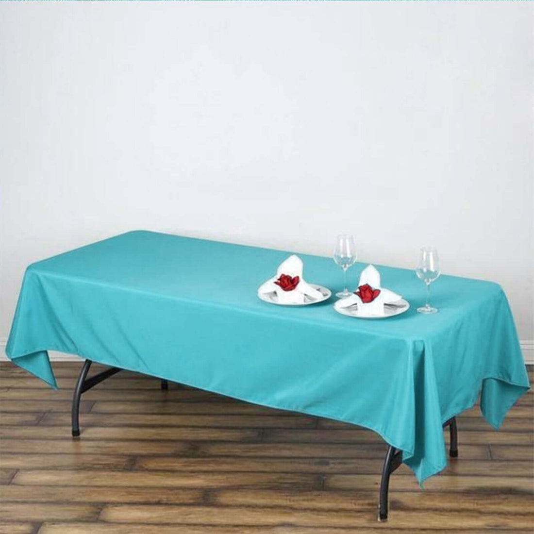 Turquoise tablecloth draped over a table with plates and glasses.