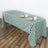 Green and white checkered tablecloth draped over a table with plates and mugs.