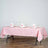 Pink checkered tablecloth set for dining with elegant napkins and glasses.