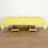 Yellow tablecloth draped over a wooden table with glasses and napkins.