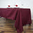Burgundy tablecloth draped over a dining table with elegant napkin decor.