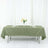 Olive green tablecloth draped over a table with plates and a flower centerpiece.