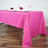 Pink tablecloth draping a table set for dinner with folded napkins and glasses.