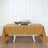 Table with a golden tablecloth set for dining and decorated with flowers and candles.