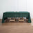 Green tablecloth draped over a wooden table with candles on a plain backdrop.