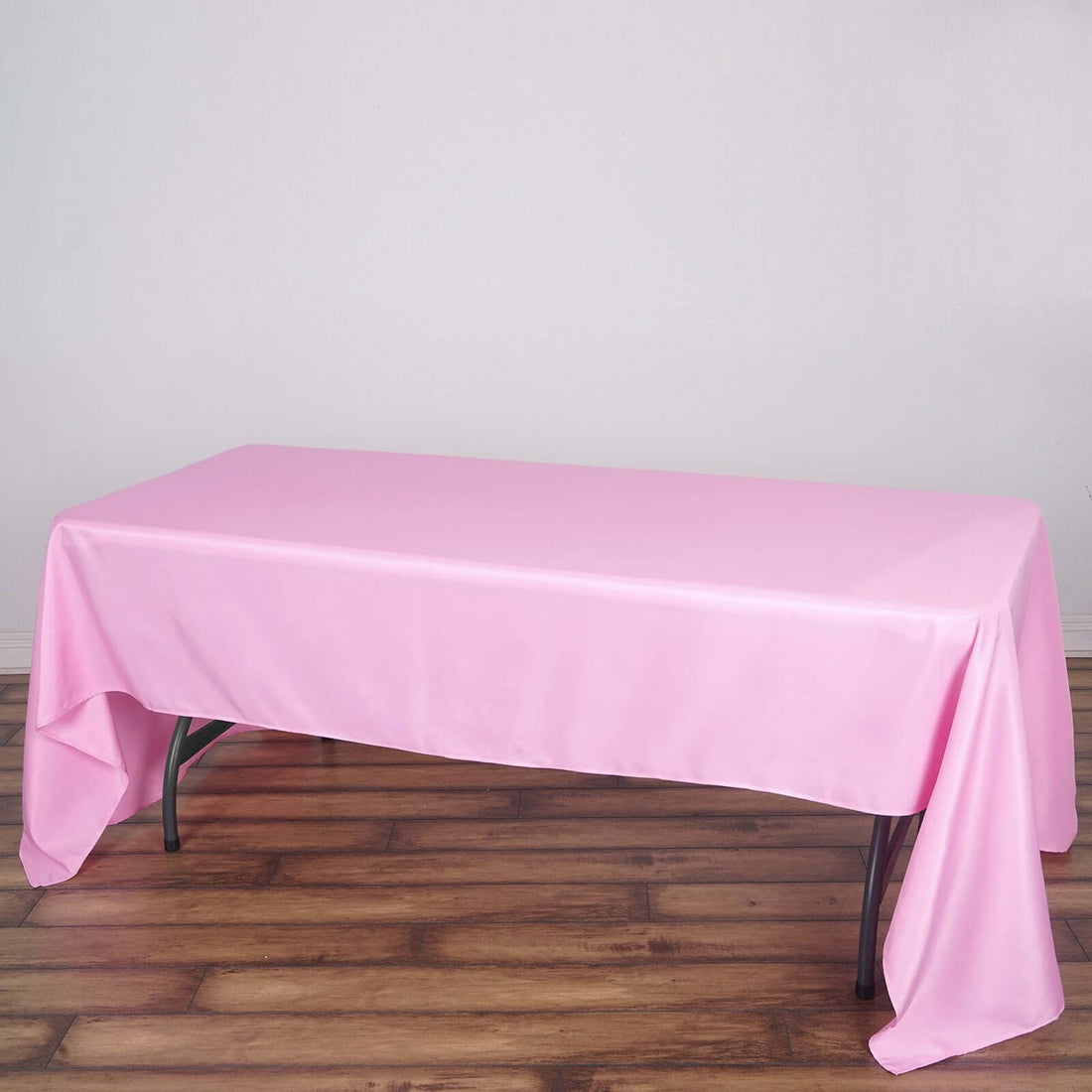 Pink tablecloth draped over a folding table in a studio setting.