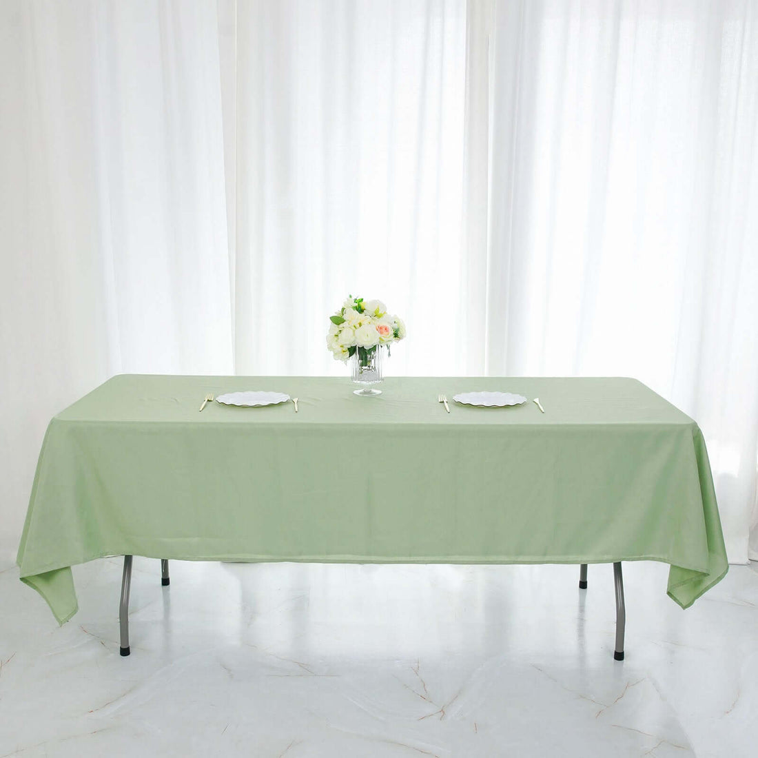 Green tablecloth draped over a table with a floral centerpiece and plates.