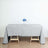 Gray tablecloth draped over a wooden table with a vase of blue flowers.
