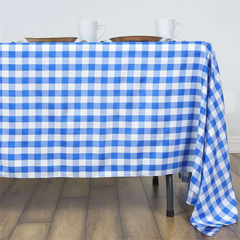 Blue and white checkered tablecloth draped over a table with dishes and cups.