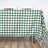 Green and white checkered tablecloth draped on a table with dishes on top.