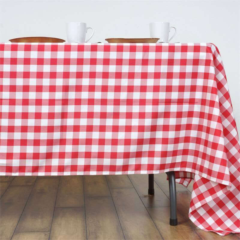 Red and white checkered tablecloth draped over a table with dishes and cups.