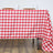 Red and white checkered tablecloth draped over a table with dishes and cups.