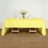 Yellow tablecloth draped over a wooden table with decorative elements.