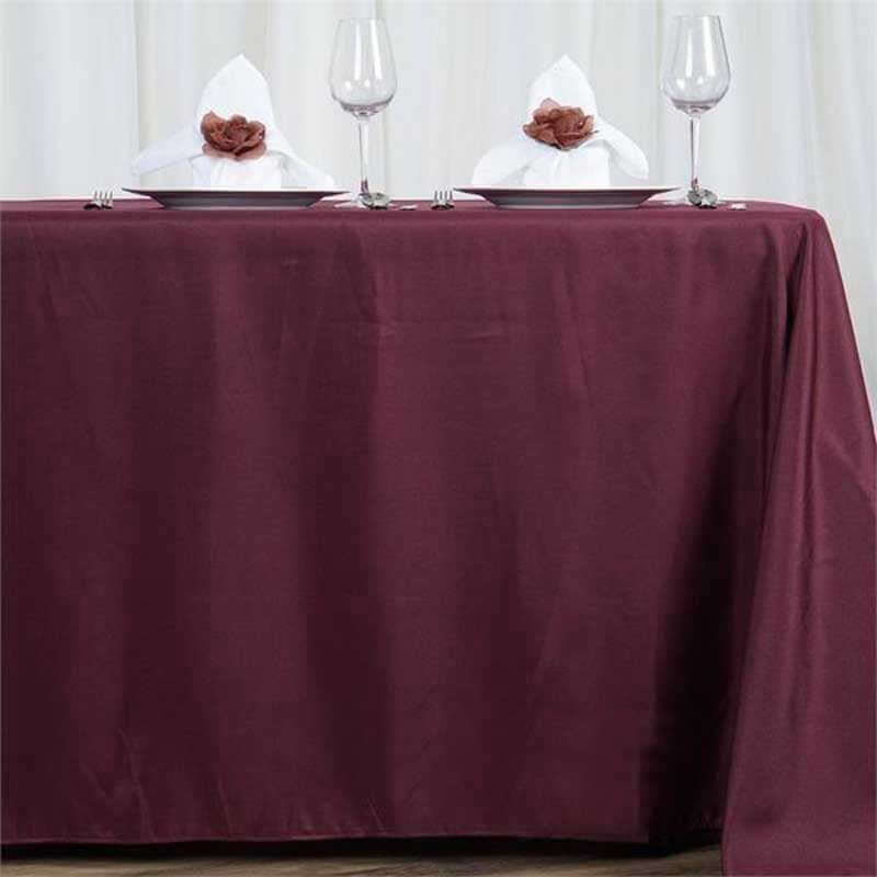 Burgundy tablecloth with elegant white napkins and wine glasses set for dining.