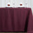 Burgundy tablecloth with elegant white napkins and wine glasses set for dining.