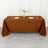Brown tablecloth on a dining table with plates, glasses, and a flower vase.