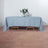 Light blue tablecloth draping over a wooden table with a vase of flowers