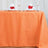 Orange tablecloth set with glassware and decorated napkins.