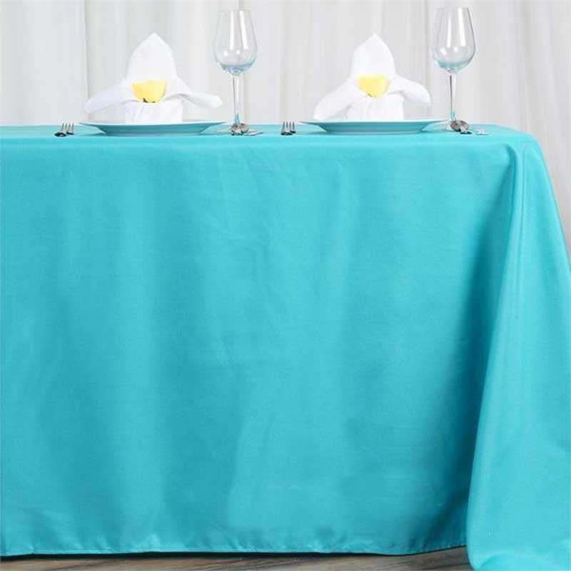 Turquoise tablecloth with elegant napkin presentation on a dining table.