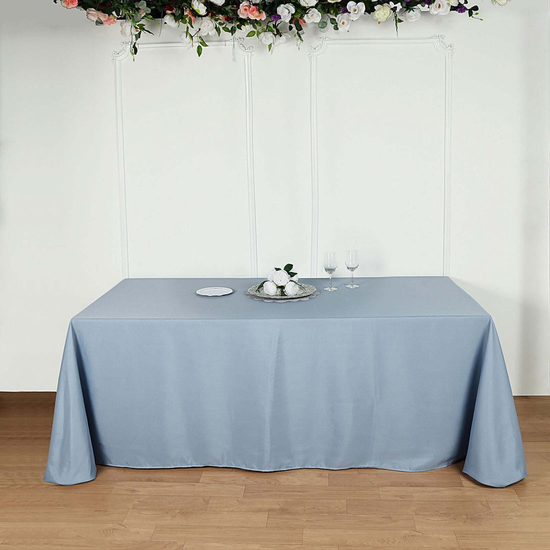Blue tablecloth draped over a table with decorative items and glasses.