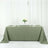 Olive green tablecloth draped over a table with plates and a floral centerpiece.