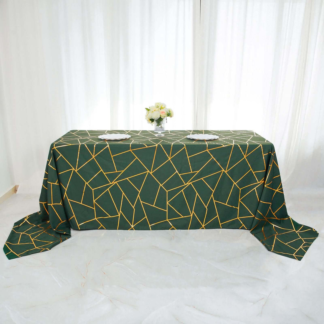 Green tablecloth with geometric gold lines on a styled table setting.