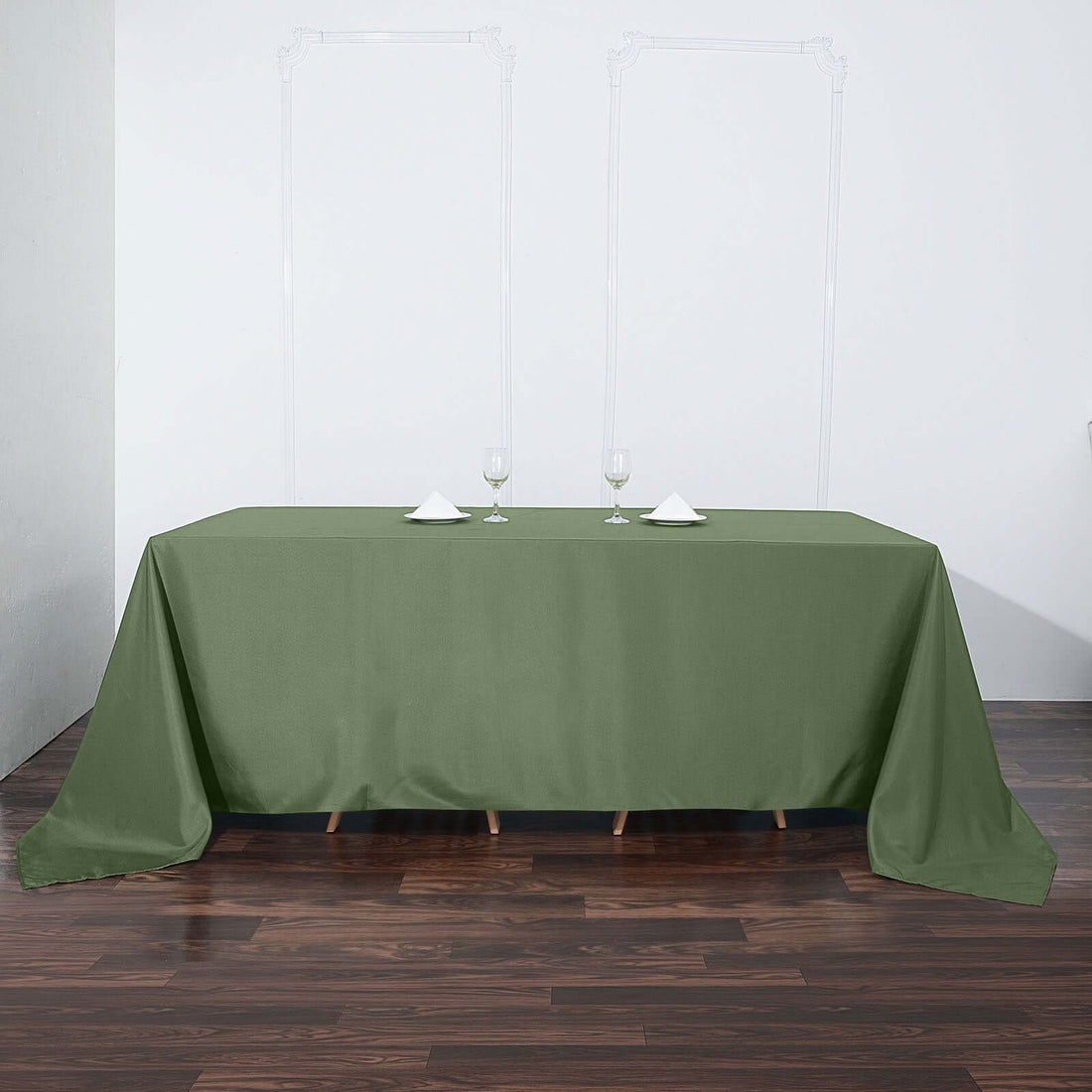 Green tablecloth draped over a table with wine glasses and napkins.