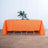Orange tablecloth draped over a table with a plant centerpiece