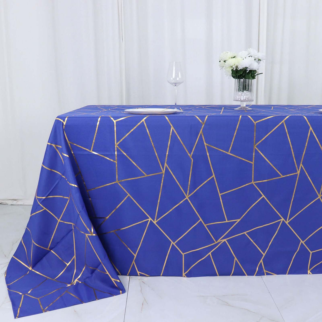 Blue geometric tablecloth with gold accents on a white backdrop.