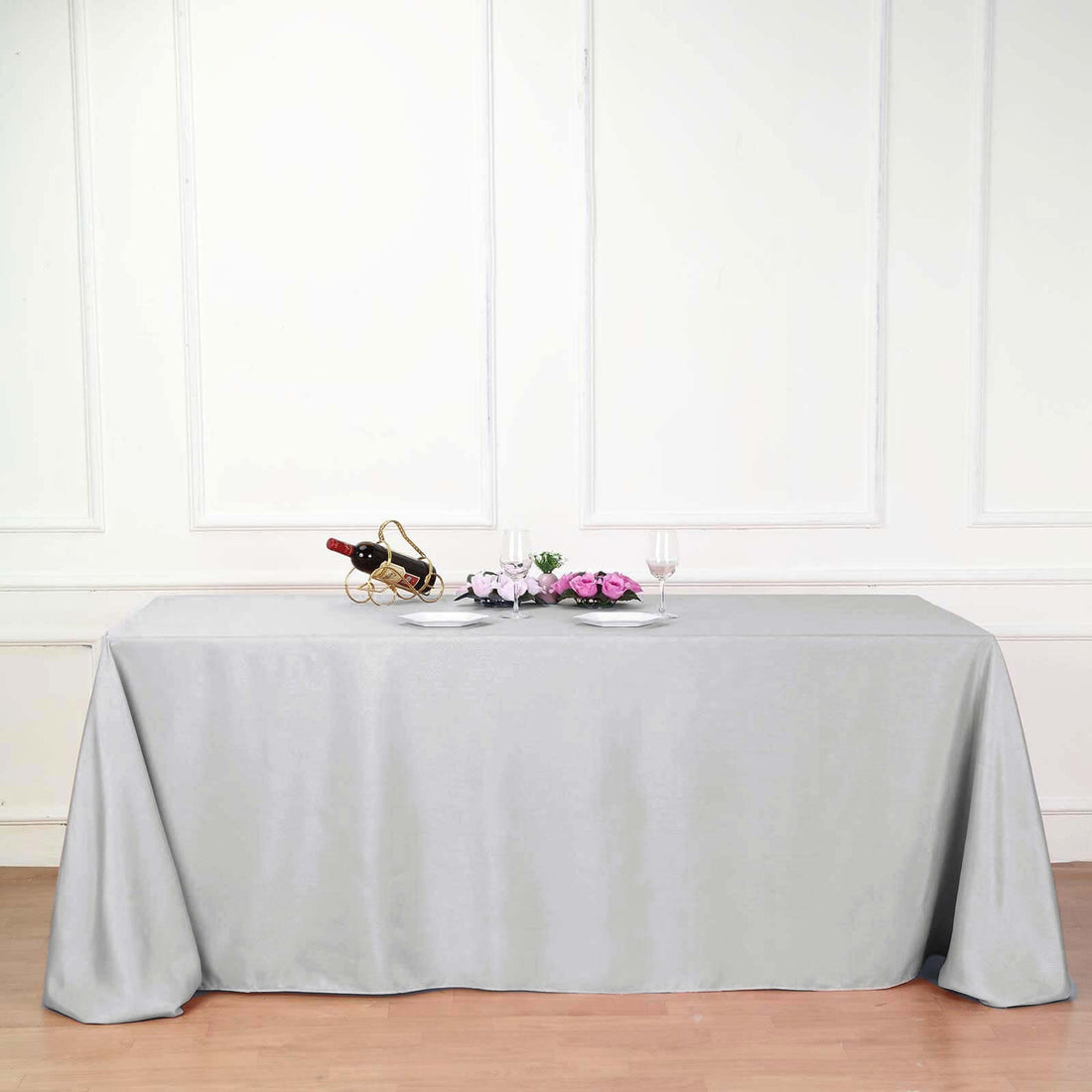 Elegant gray tablecloth draped over a table with wine and flowers.