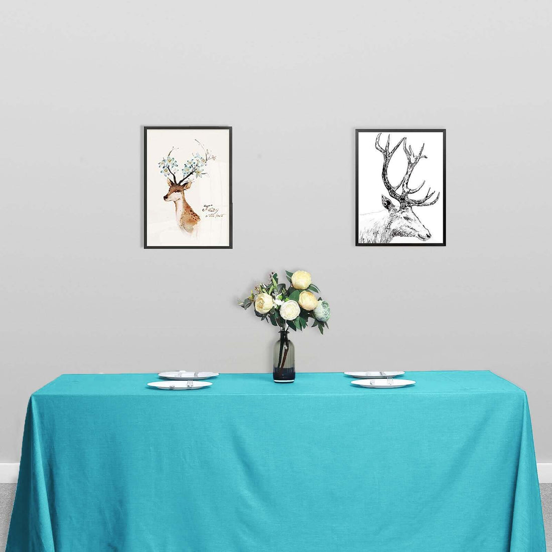 Table set with a turquoise tablecloth, floral centerpiece, and framed deer art on the wall.