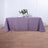 Purple tablecloth draped over a table with a vase and flowers.