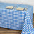 Blue and white checkered tablecloth on a wooden table with plates and glasses.