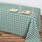 Green and white checkered tablecloth on a wooden table with plates and glasses.
