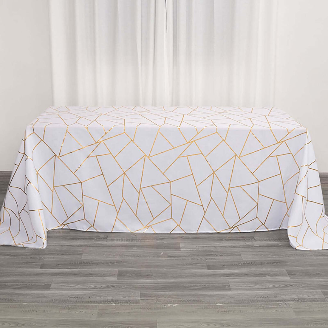 White tablecloth with gold geometric design on a wooden floor.