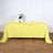 Yellow tablecloth draped over a wooden table with a vase and glass on top.