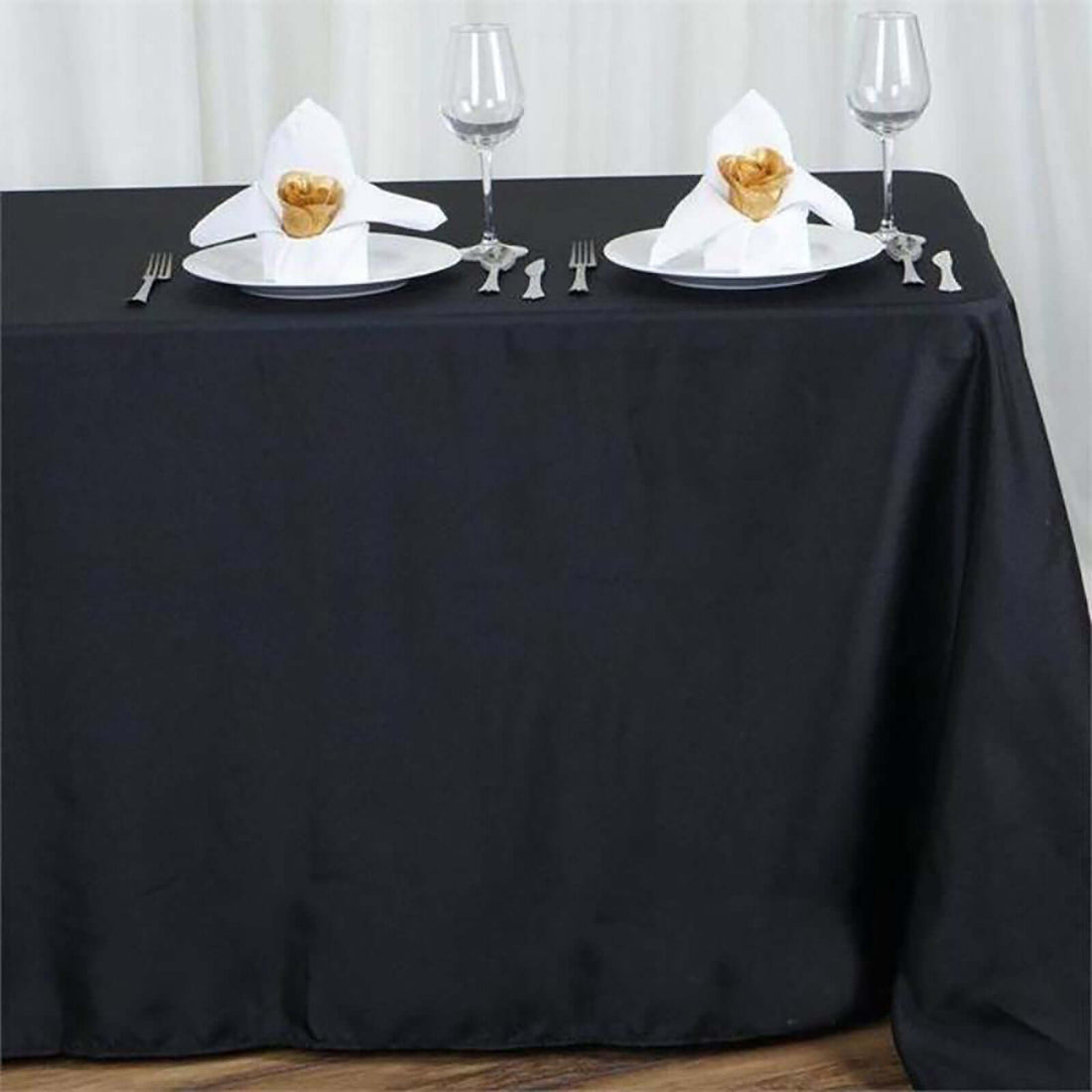 Elegant black table setting with decorative napkin folds and wine glasses.