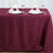Elegant burgundy tablecloth set with plates and napkins for dining.