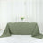 Olive green tablecloth draped over a table with plates and a vase of flowers.