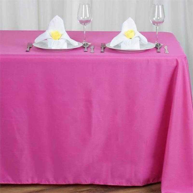 Pink tablecloth set with plates, napkins, and glasses for dining.