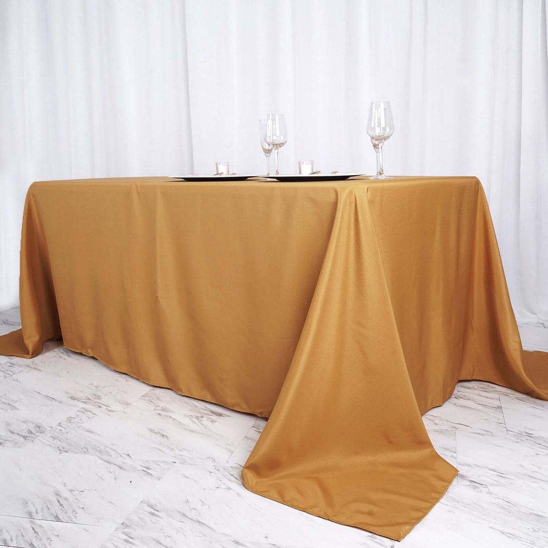 Elegant gold tablecloth draped over a table with glasses set for dining.