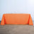 Orange tablecloth draped over a long table in a minimalist setting.