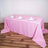 Pink tablecloth draped over a dining table set with plates and glasses.