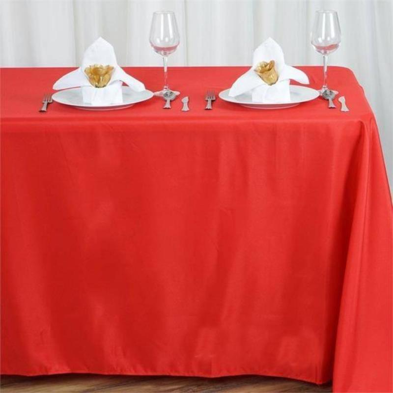 Red tablecloth set with elegant napkin folds and place settings.