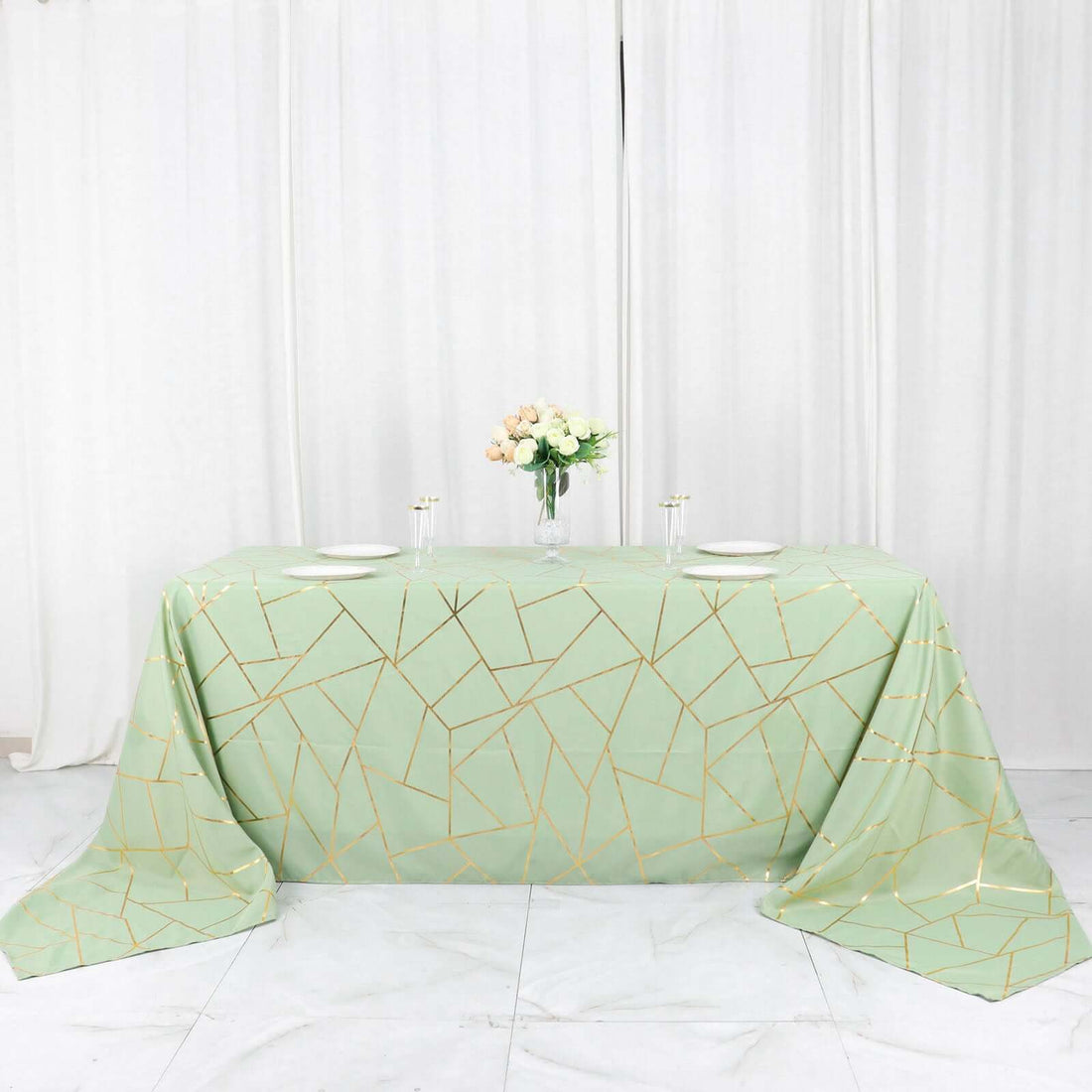 Mint green tablecloth with gold geometric pattern on a white table.