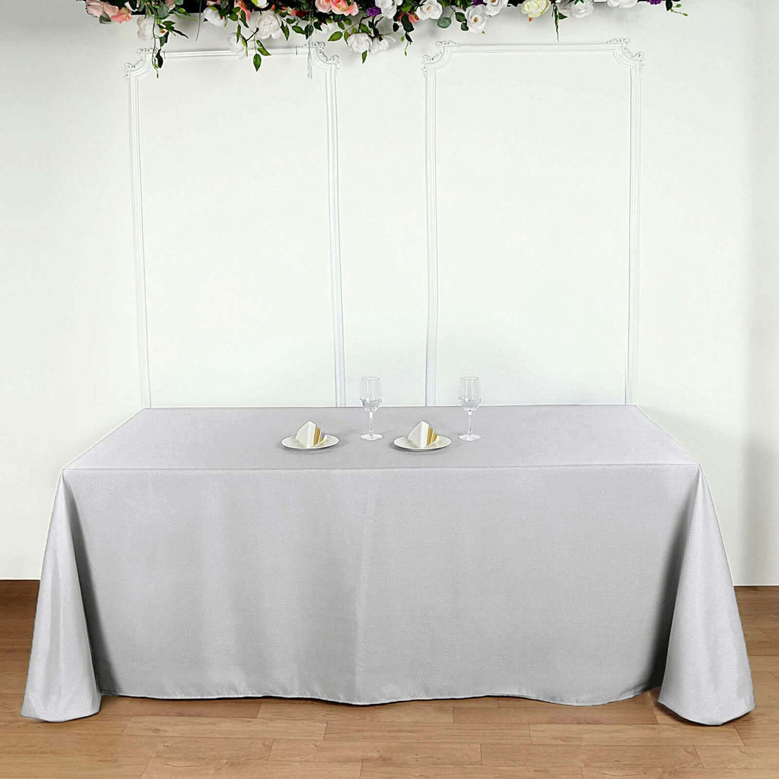 Gray tablecloth draped over a table with plates and glasses on it.