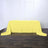 Yellow tablecloth on a wooden floor, elegantly draped with napkins and glasses.